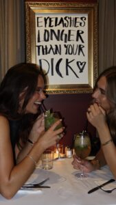 To gæster griner over cocktails ved bordet hos Petit Prix