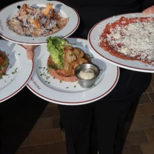 Tjener bærer tallerkener med carpaccio og tartar hos Petit Prix